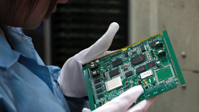 Trabajadora examina una placa madre.