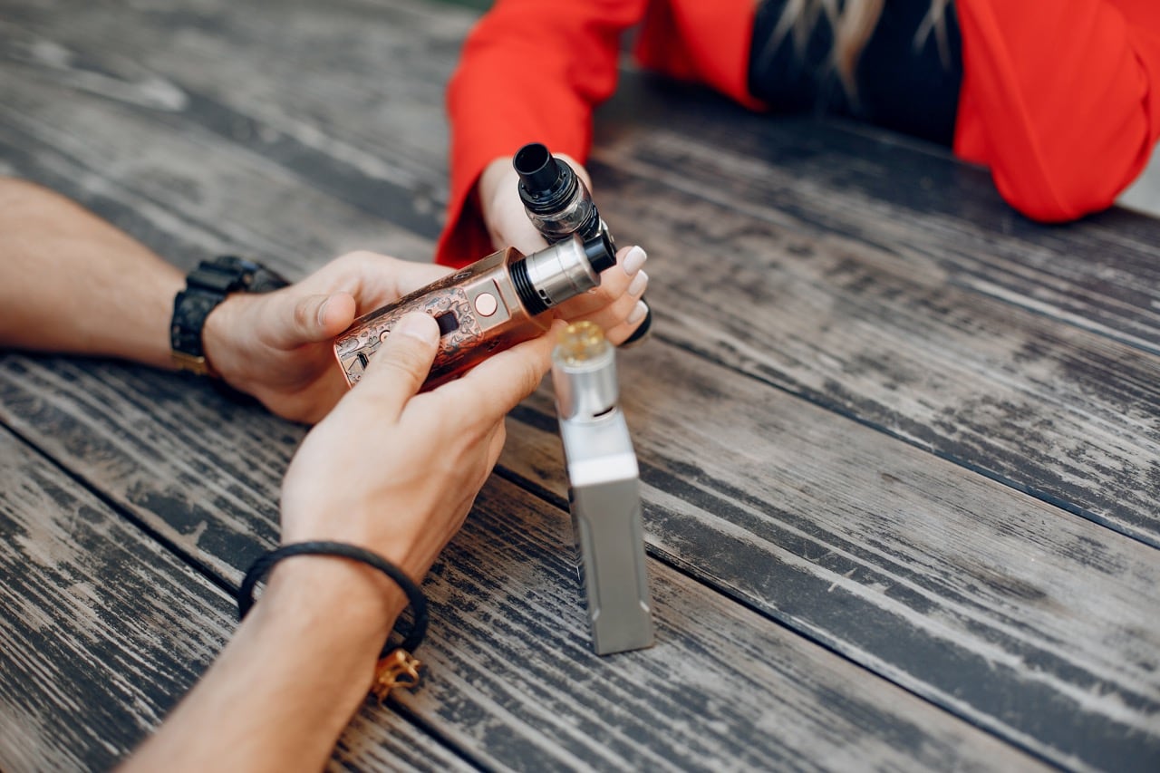 Stylish couple in a city. Two people use the electronic cigarette