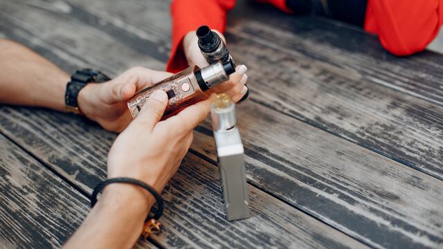 Stylish couple in a city. Two people use the electronic cigarette