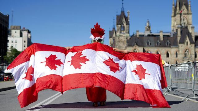 Un hombre camina envuelto por banderas de su país en Ottawa, la capital de Canadá.