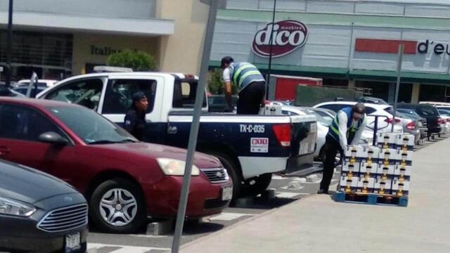 Empleados de una plaza comercial subieron los cartones de cerveza a la patrulla.