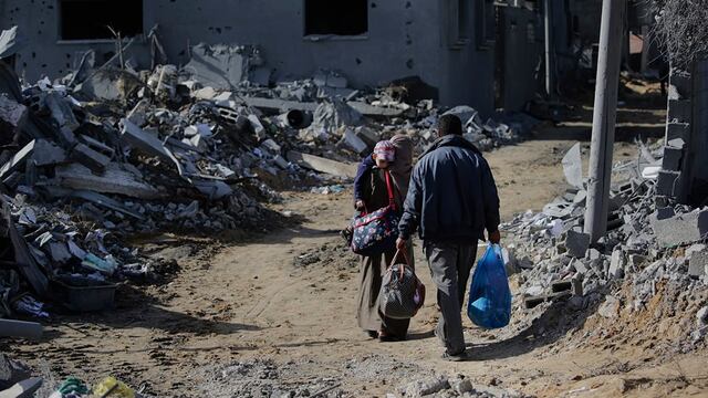 Los palestinos pasan junto a los escombros de las casas destruidas tras los ataques aéreos israelíes en el este de Khan Younis