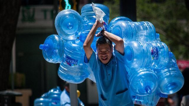 Un hombre carga varios garrafones de agua vacíos.