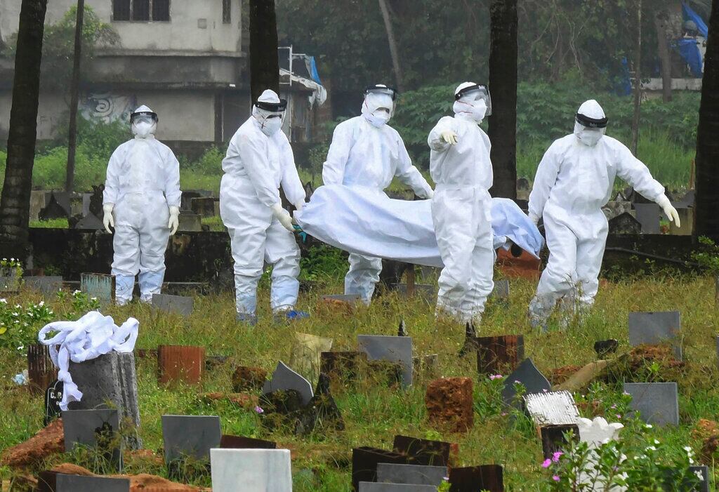 Personas con trajes de protección con cuerpo de menor infectado por virus Nipah.