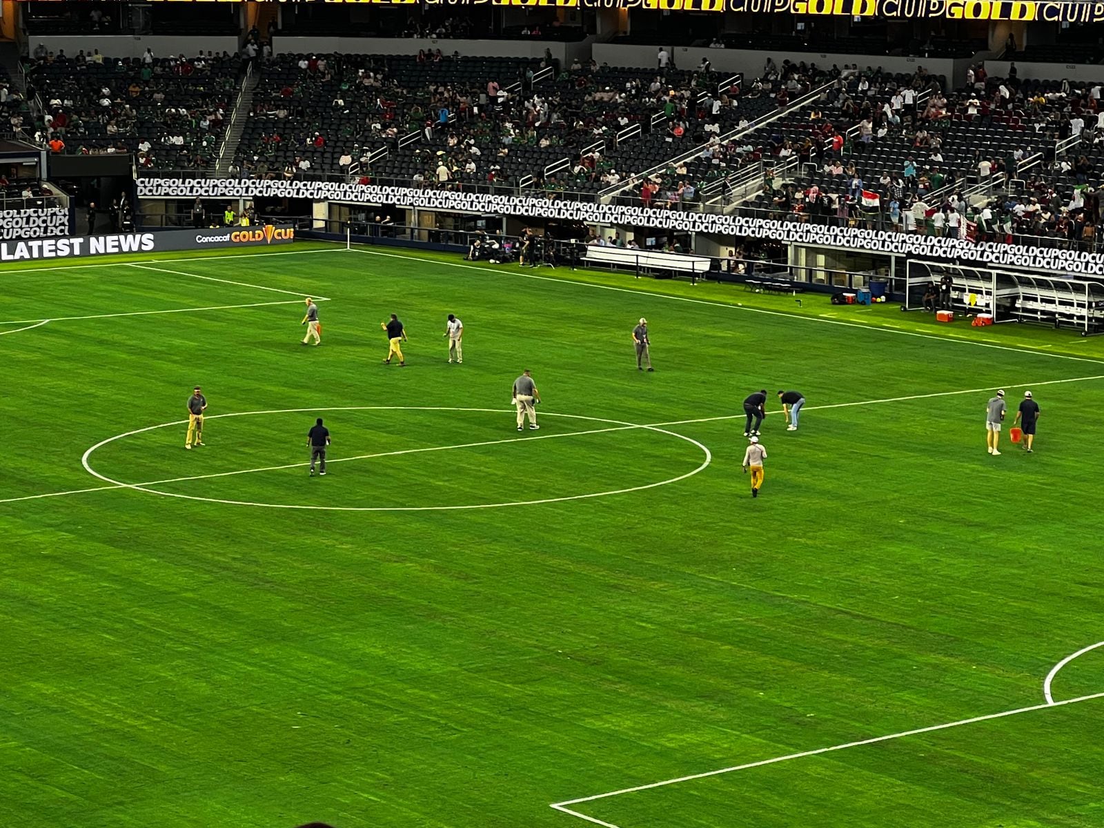 Trabajadores del AT&T Stadium intentan reparar el daño en la cancha previo al partido entre México y Costa Rica.