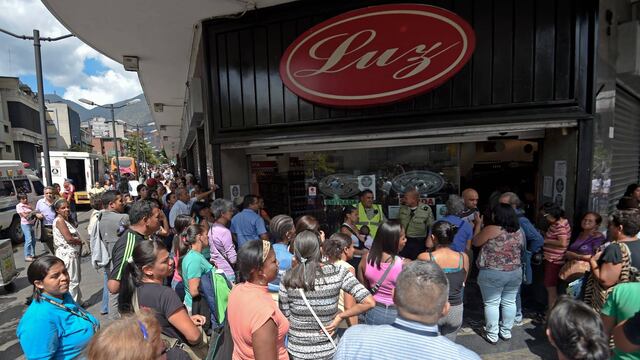 Gente aguarda afuera de un supermercado en Caracas para poder comprar productos básicos.