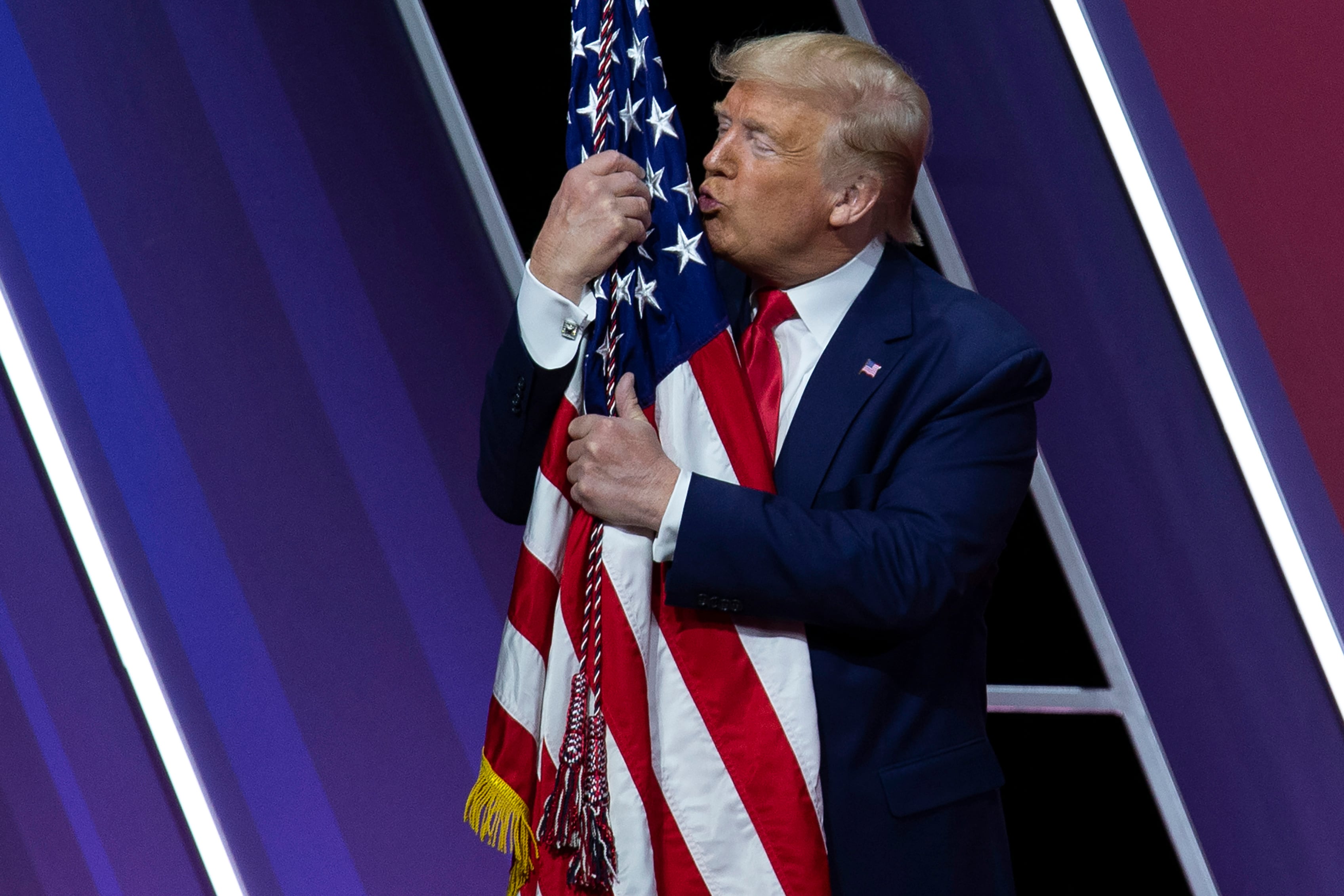 Donald Trump besa la bandera de los Estados Unidos en un acto público.