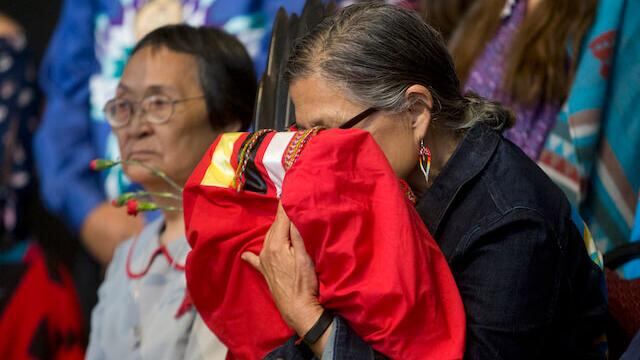Mujer indígena abraza copia del informe "National Inquiry into Missing and Murdered Indigenous Women and Girls" presentado por el primer minsitro Justin Trudeau