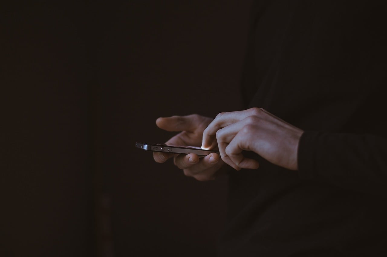 Un hombre sostiene un teléfono inteligente con las manos.
