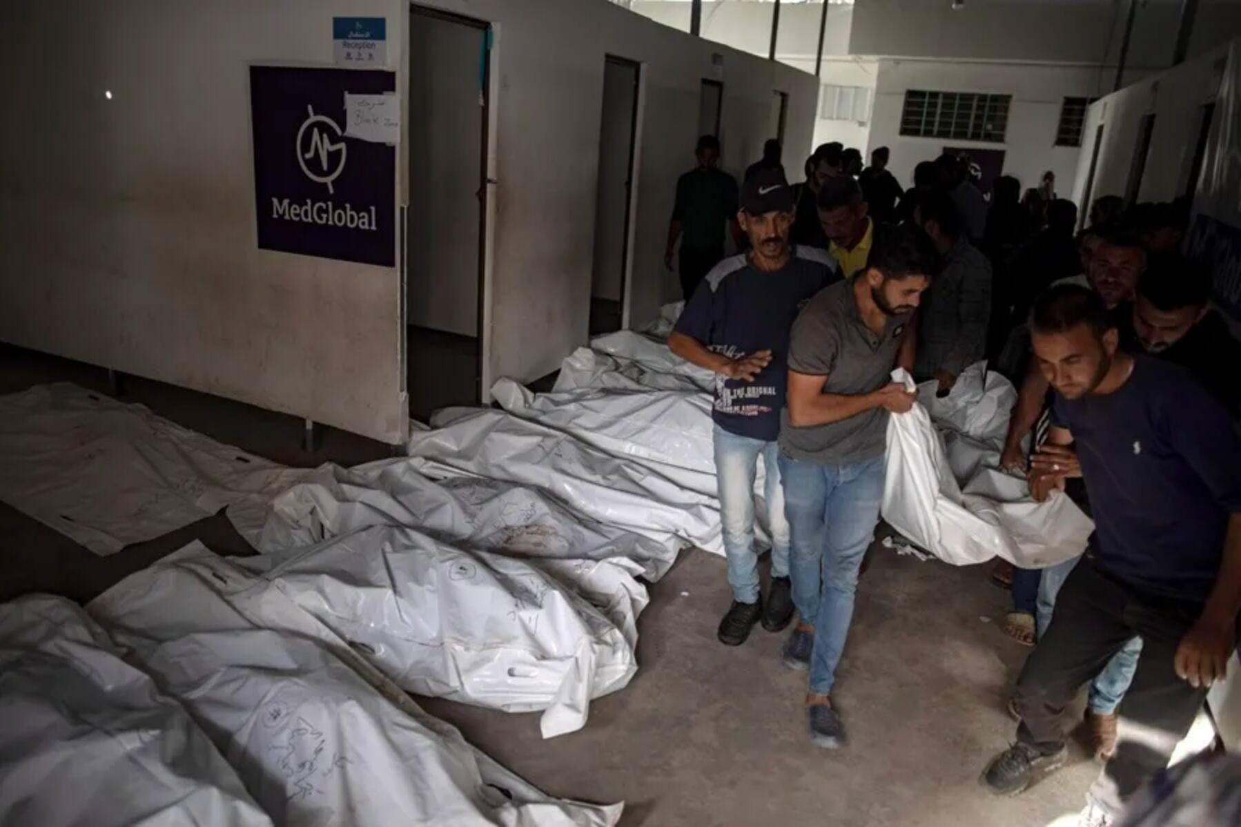 Palestinos trasladan los cadáveres de algunas de las víctimas del ataque israelí contra un campamento para desplazados en Rafah