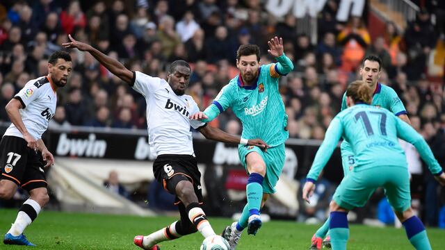Messi disputa un balón con jugadores del Valencia