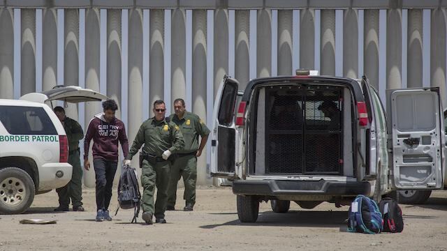 Elementos de la Patrulla Fronteriza detienen a un hombre que cruzó el muro hacia Estados Unidos desde Tijuana.