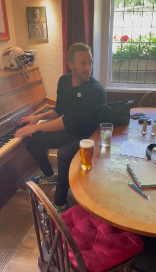 Chris Martin cantando en un bar para una pareja
