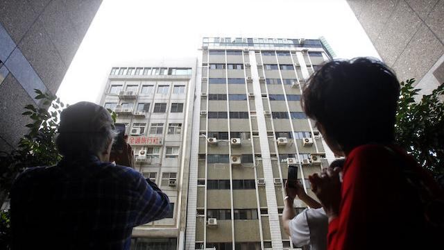 Personas toman fotos a un edificio dañado por el terremoto.