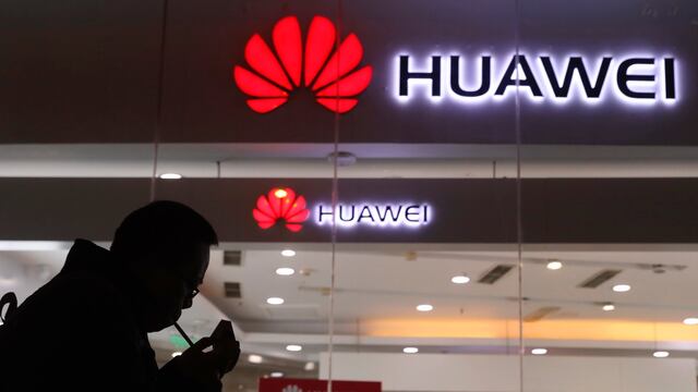 Un hombre enciende un cigarrillo frente a una tienda de Huawei en Pekín.