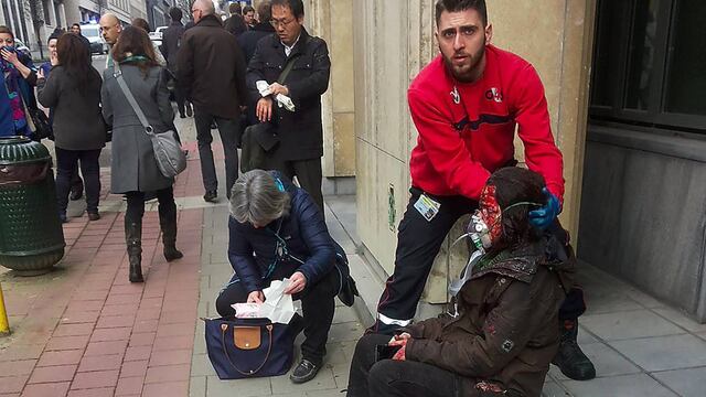 Un guardia de seguridad privada ayuda a una mujer herida en el atentado ocurrido en el metro de Bruselas.