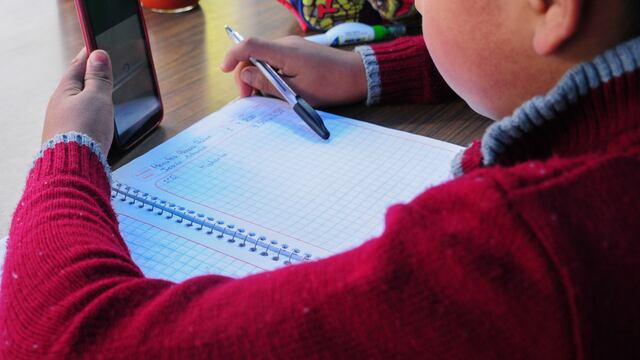 Pedro observa su celular mientras espera que cargue un video para completar una de sus clases
