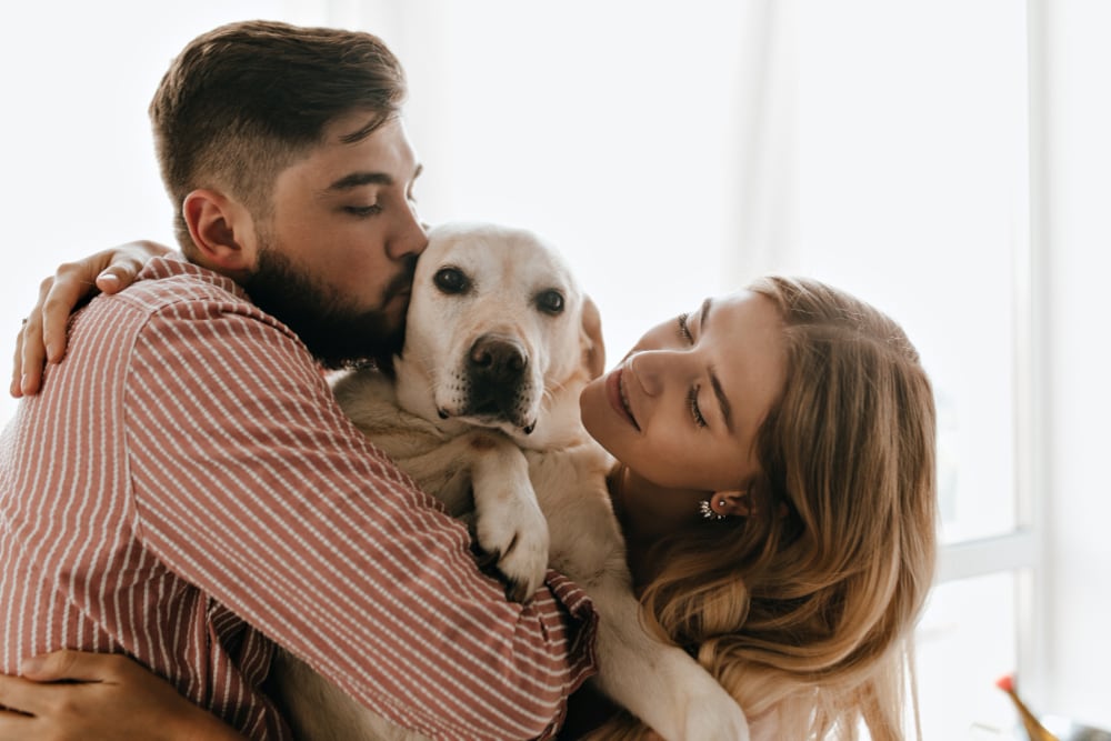 Pareja dándole cariño a su perro.