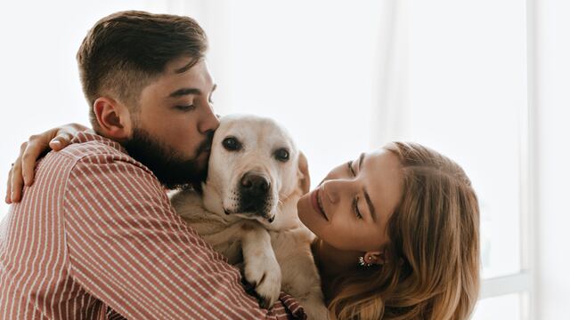 Pareja dándole cariño a su perro.