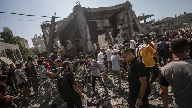 Palestinos buscan a personas desaparecidas bajo los escombros de un edificio destruido tras un ataque aéreo israelí en el campo de refugiados de Al Bureij