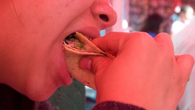 Una persona come tacos de carnitas de puerco.