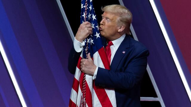 Trump besa la bandera de Estados Unidos en un acto público.
