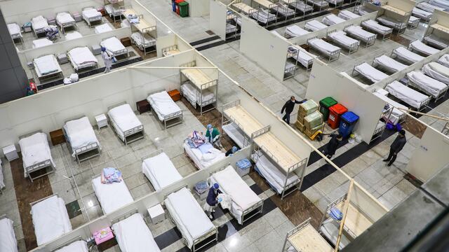Trabajadores de un hospital en Wuhan preparan camas para recibir a personas enfermas de coronavirus.