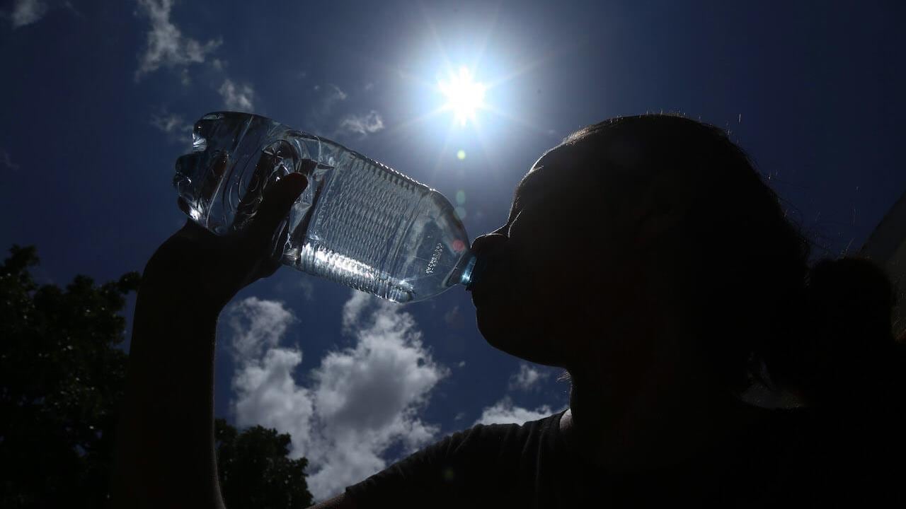 Persona tomando agua bajo el sol
