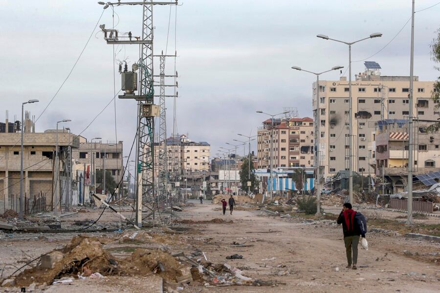 Palestinos caminan entre escombros a lo largo de la carretera Salah al-Din, en el sur de la Franja de Gaza