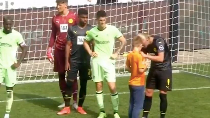Erling Haaland firma la camiseta de un niño en pleno partido