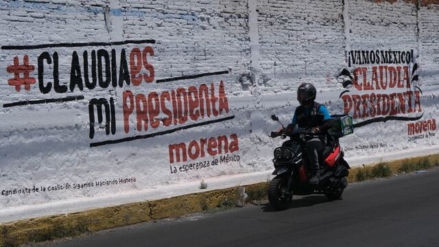 Con el hashtag "Claudia es mi Presidenta", un motociclista transita frente a bardas rotuladas en la alcaldía Iztapalapa