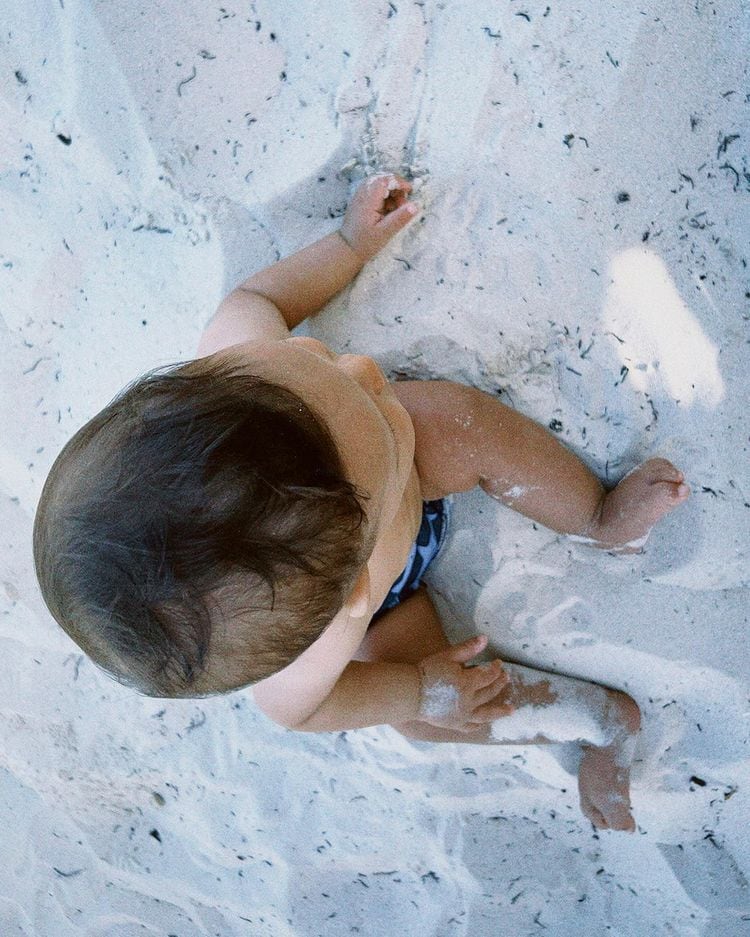 Mar, el hijo de Yuya sentado en la arena.