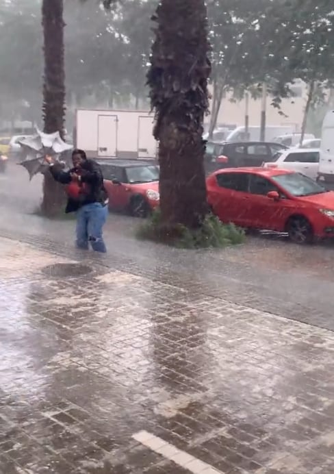 Sostiene su paraguas en medio de la lluvia