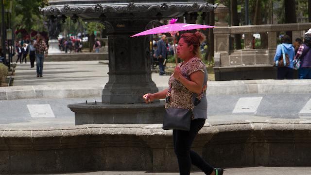 Una mujer se cubre del sol en la Alameda Central, alcaldía Cuauhtémoc.