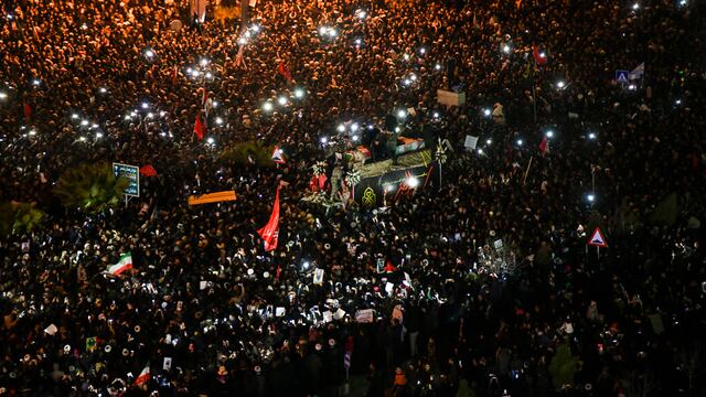 Dolientes rodean un camión con los ataúdes del general Qassem Soleimani y sus compañeros, cubiertos por banderas, en la ciudad sagrada de Qom, al sur de la capital de Irán, Teherán.