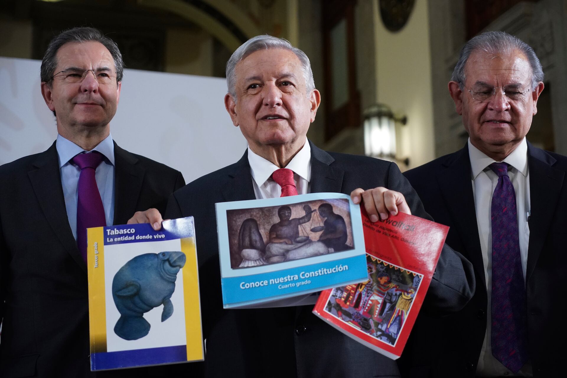 AMLO sostiene ejemplares de los nuevos libros de texto gratuitos.