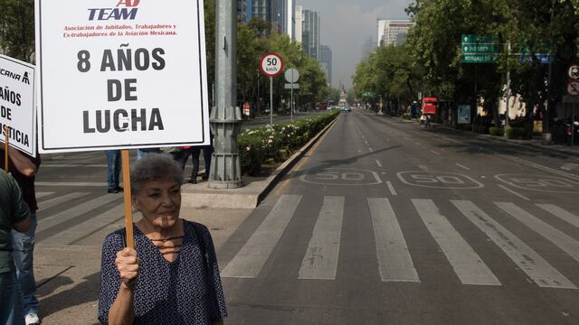 Una mujer sostiene un cartel pidiendo solución al conflicto en Mexicana de Aviación.