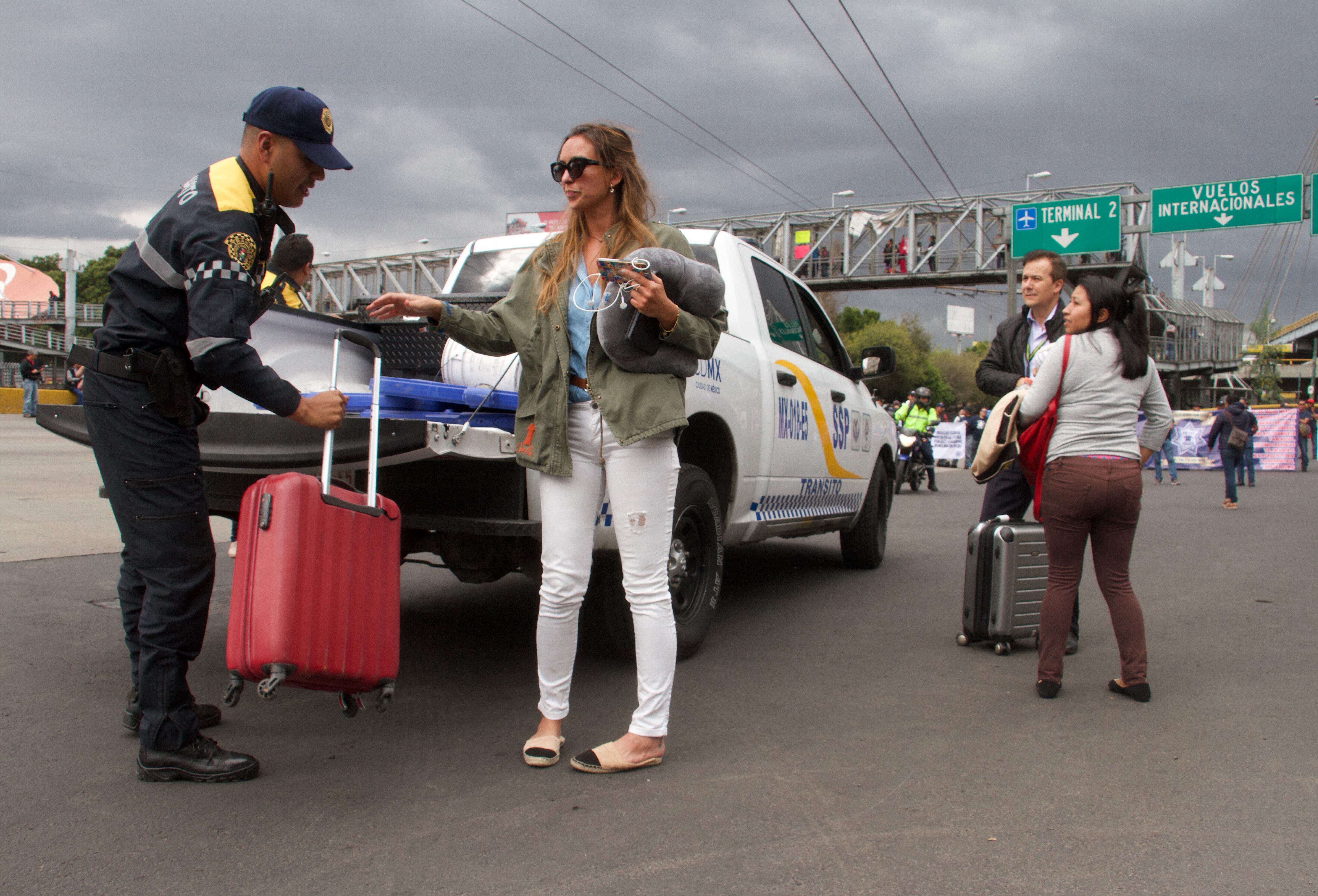 Policías de la Ciudad de México auxilian a pasajeros para su traslado a AICM ante bloqueo de policías federales.