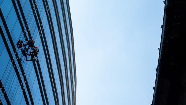 Dos limpiavidrios laboran en un edificio de Periférico Sur en la alcaldía Álvaro Obregón.