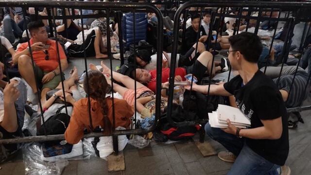 Un empleado de Huawei entregando baterías portables en la fila frente a una Apple Store.