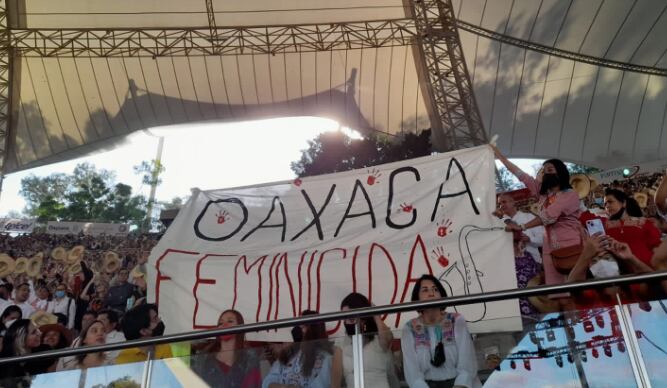 María Elena Ríos protesta con manta de Oaxaca Feminicida en Guelaguetza 2022; se la quitan y la golpean.