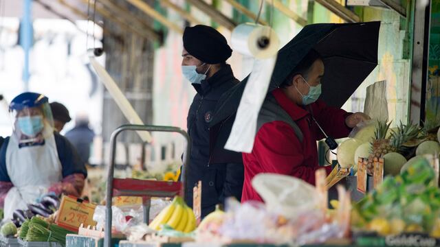 Both workers and shoppers take precautions by using face masks and social distancing to stay safe from COVID-19 at a produce market in Vancouver, British Columbia, Friday, March 27, 2020. (Jonathan Hayward/The Canadian Press via AP)