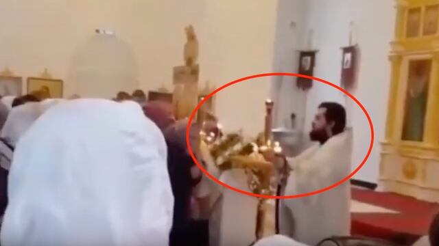 Con una manguera, este cura bendice a sus fieles.