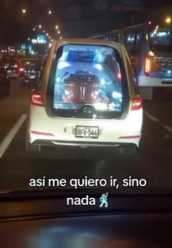 Carroza fúnebre llevando ataúd con todo y fiesta