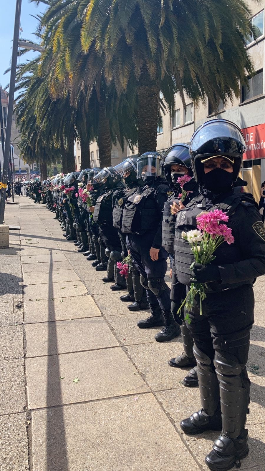 Policías sujetan flores en marcha feminista del 8 de marzo
