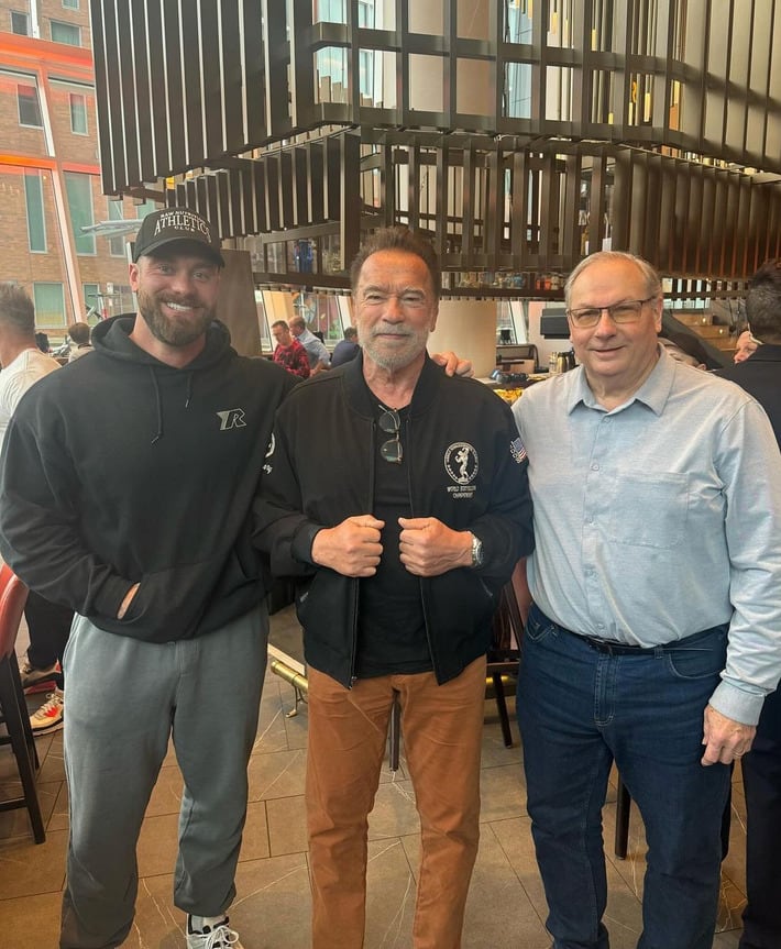 Cbum con Arnold Schwarzenegger y su papá.