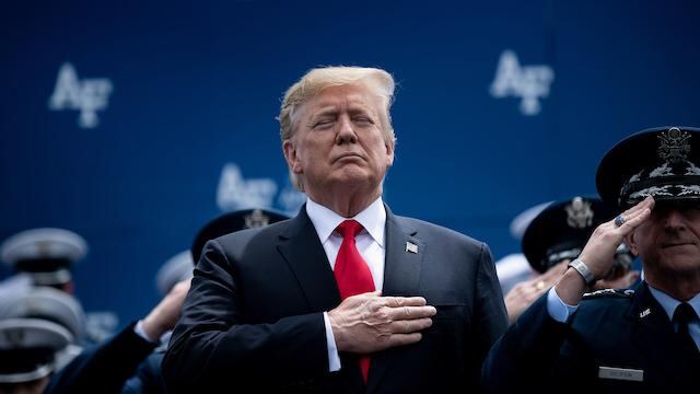 El presidente Trump saluda durante el himno de su país.