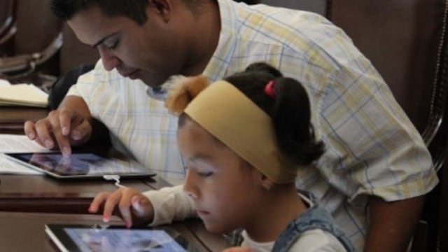 Padre e hija con dispositivos móviles