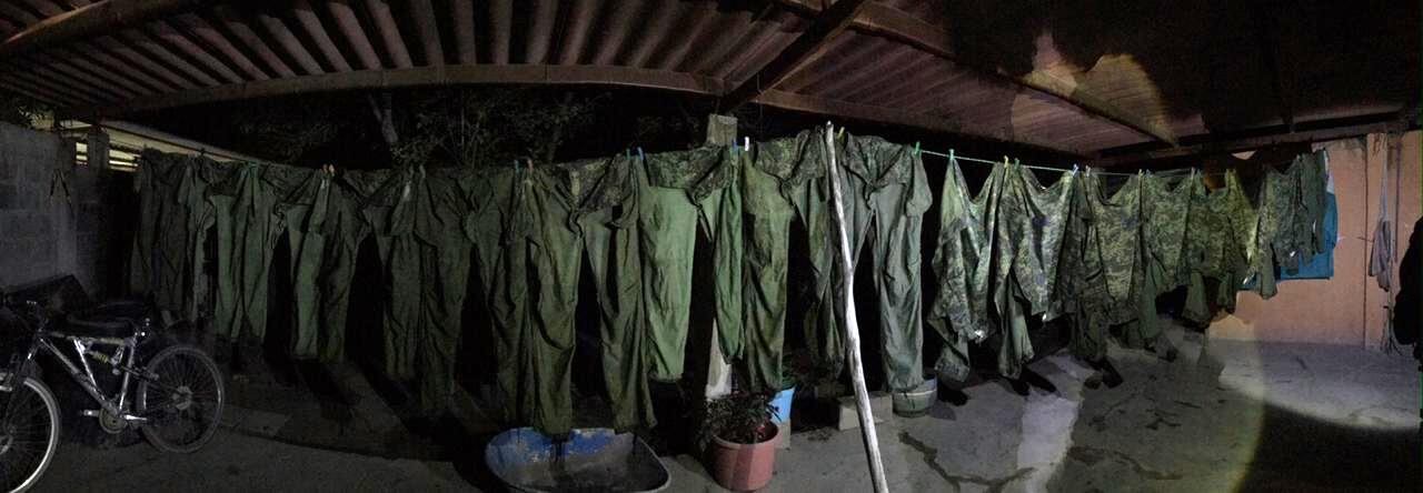 Una gran cantidad de uniformes militares y ropa de fatiga se encontraba colgada en el patio de la casa.