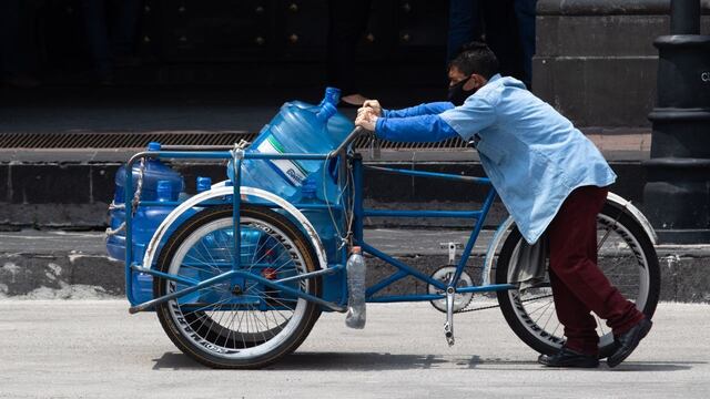 Un hombre reparte agua embotelalda en un triciclo en las calles del Centro Histórico.